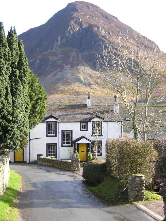 a white house with a mountain in the background at Kirkstile Inn in Loweswater