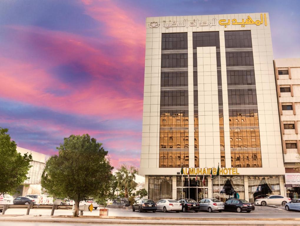 Al Muhaidb Al Olaya Suites في الرياض: مبنى فيه سيارات تقف امامه
