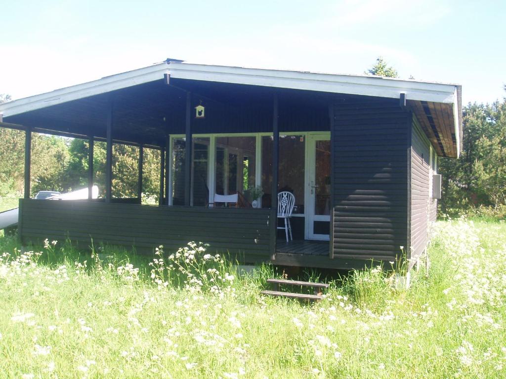 una cabaña de madera en un campo de hierba alta en Summer cottage, en Nøreng