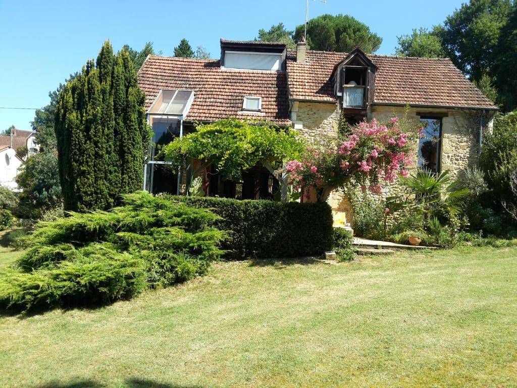 une maison avec des fleurs et des buissons dans une cour dans l'établissement Belle Demeure Sarladaise, à Sarlat-la-Canéda