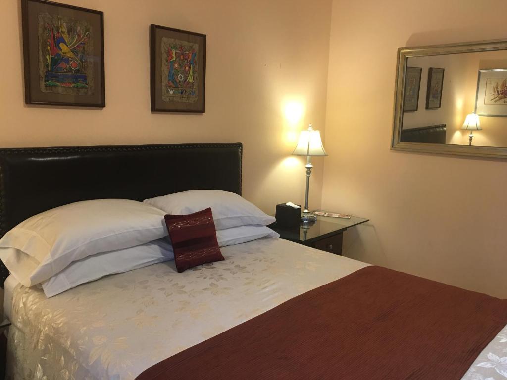 a bedroom with a bed with two pillows and a mirror at Dickinson Guest House, Guadalajara Expo in Guadalajara