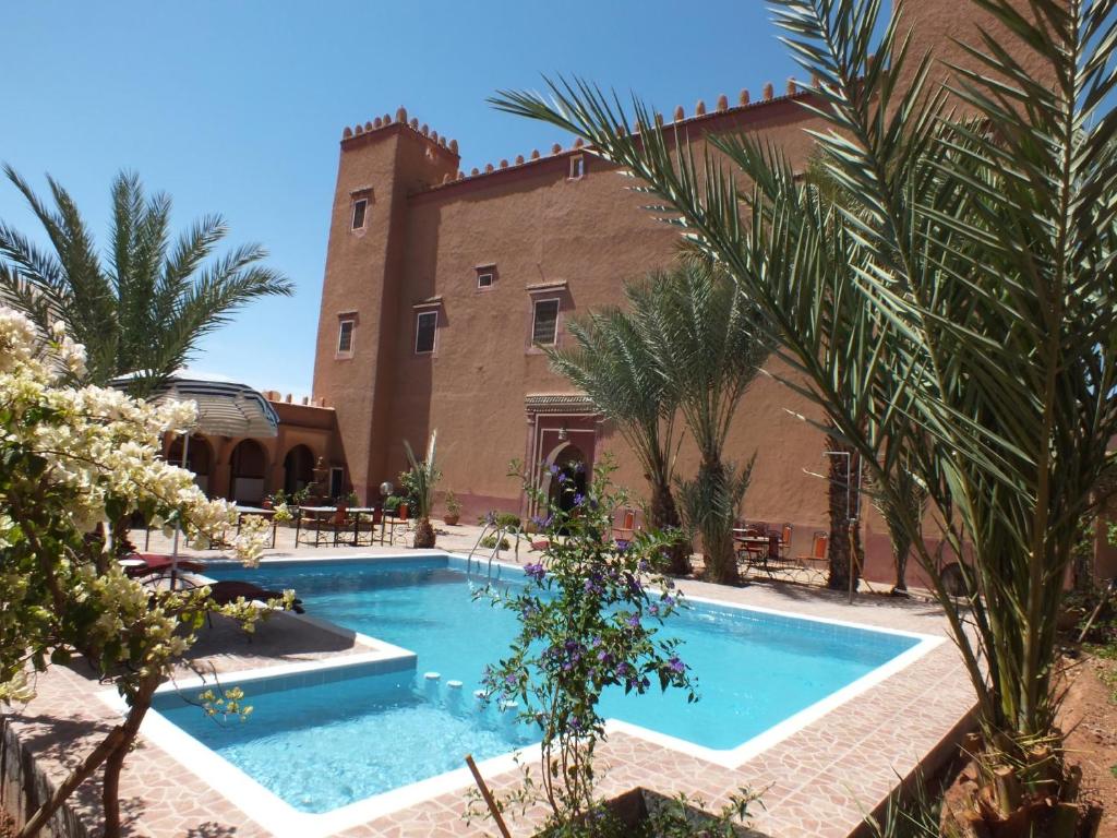 une piscine en face d'un bâtiment avec des palmiers dans l'établissement Hotel Tomboctou, à Tinghir