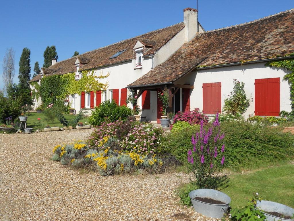 a cottage with red doors and flowers in the yard at Ferme les Rousseaux in La Belliole