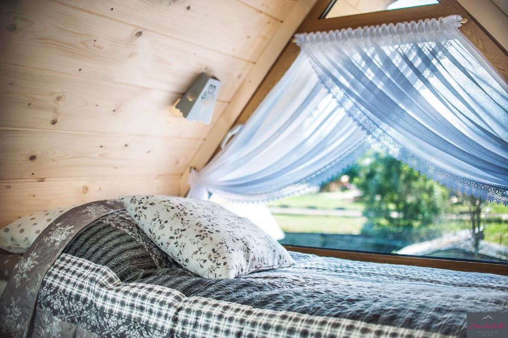 1 cama en una casa pequeña con ventana en Stachelisko - domki i pokoje en Chochołów