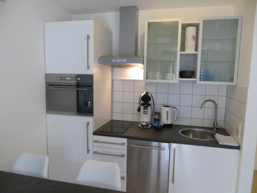 eine kleine Küche mit weißen Schränken und einem Waschbecken in der Unterkunft Ferienwohnung BELVEDERE in Rust