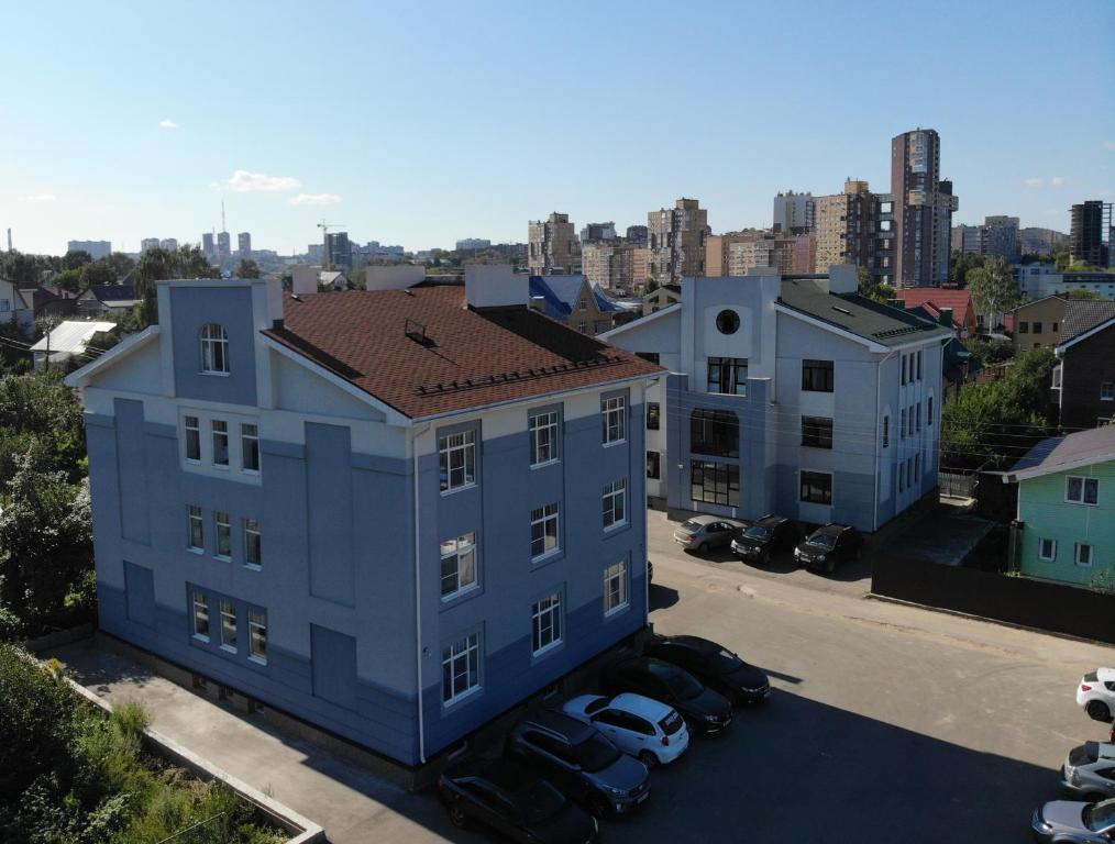 a blue building with cars parked in a parking lot at Guest House Agrodom in Nizhny Novgorod