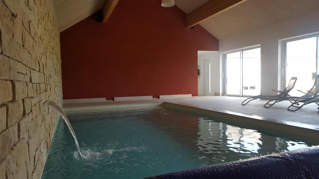 a swimming pool with chairs in a room with red walls at Agathe et Titi in Marigny-lès-Reullée