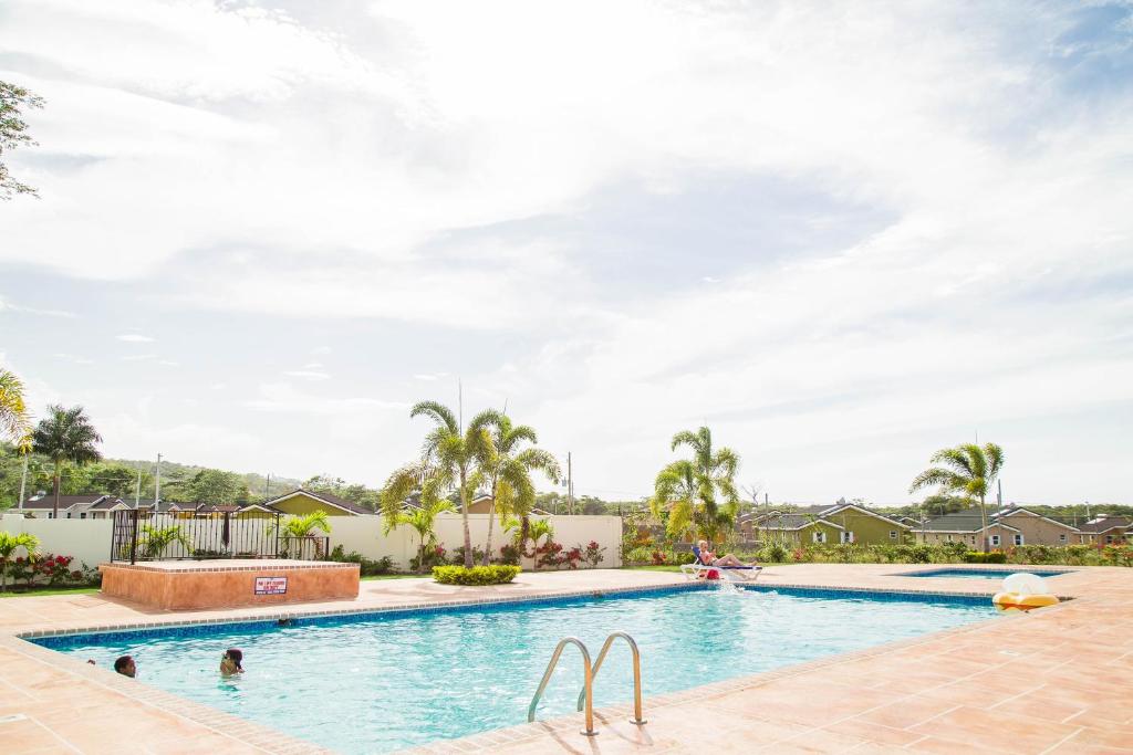 オーチョ・リオスにあるLa Casa De Playa Ocho Rios Villaのヤシの木が茂るリゾートのスイミングプール