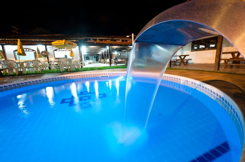 una fuente de agua en una piscina por la noche en Pousada Recanto do Prado, en Prado