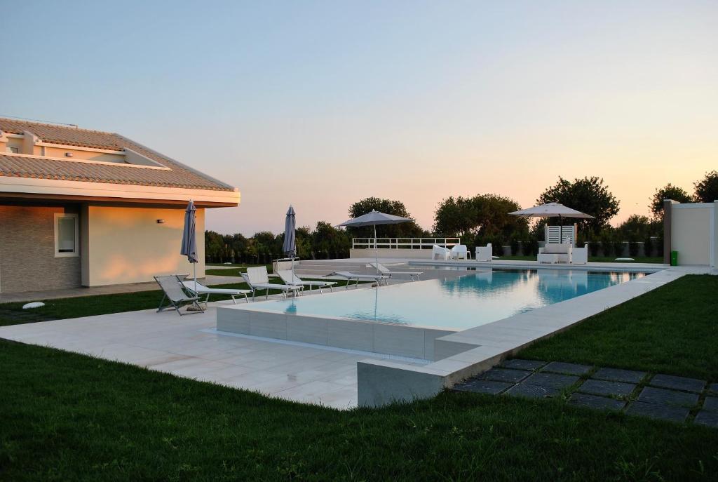 einen Pool mit Stühlen und ein Haus in der Unterkunft La Giara in Marina di Modica