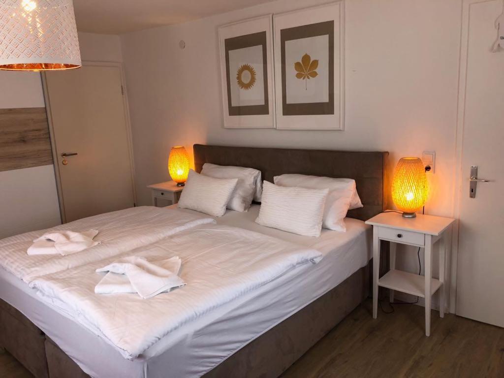 a bedroom with a large white bed with two lamps at ZUM BAHNHÖFLE Restaurant & Hotel - Albbruck Am Rhein in Albbruck