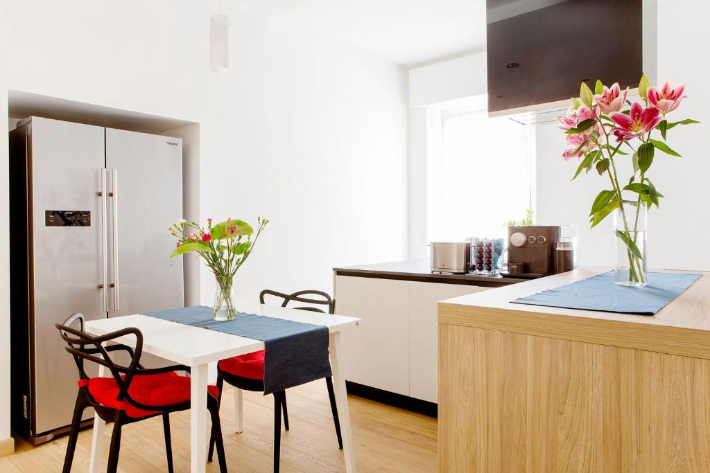 uma cozinha com uma mesa e 2 cadeiras e uma cozinha com armários brancos em B&B agli Orti em Verona