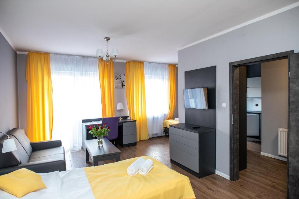 ヴジェシニャにあるApartamenty Brzezinskiのベッドとテレビが備わるホテルルームです。