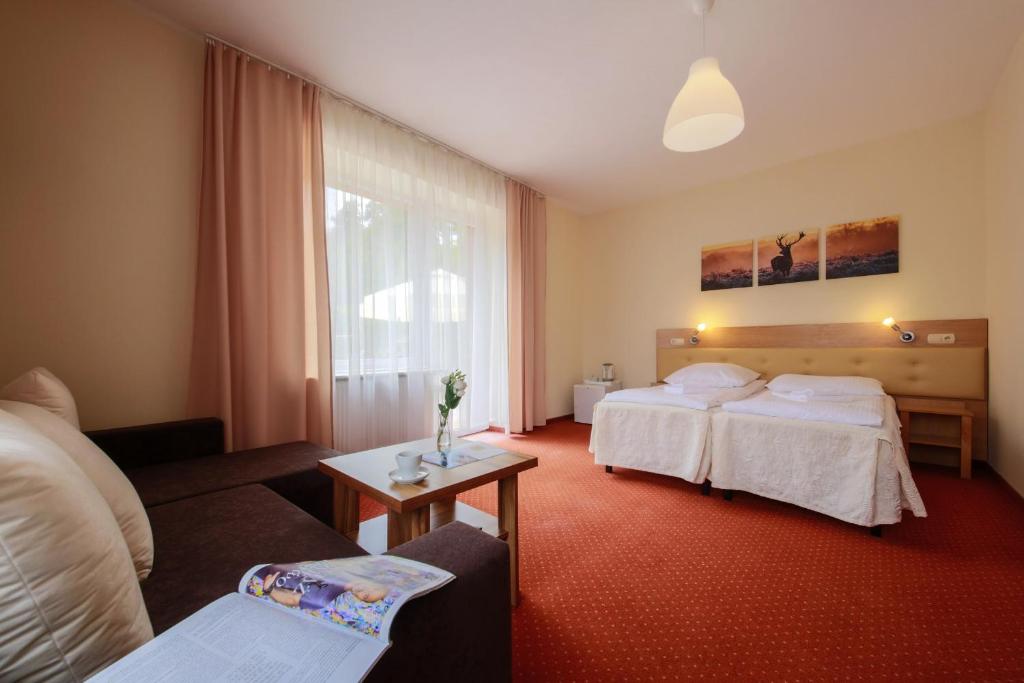 Spacious double room showing bed, sofa, coffee table with vase, and soft natural light.