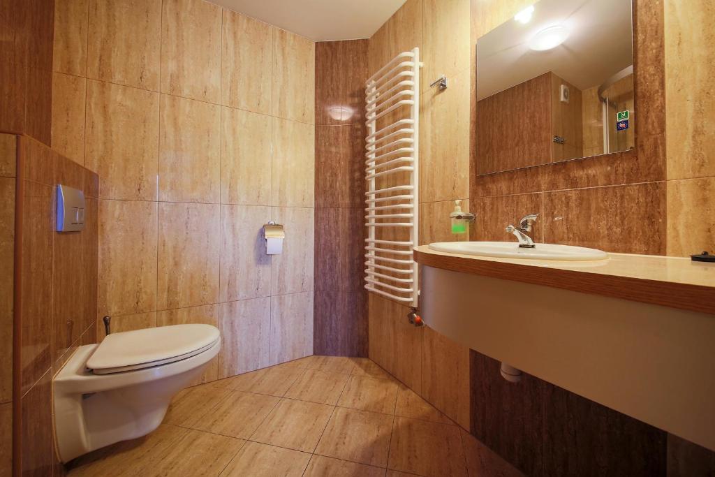 Bathroom with wall-mounted toilet, sink and heated towel rail, beige marble tiles.