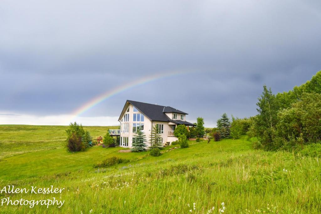 um arco-íris sobre uma casa num campo em Misty Ridge Retreat B&B em Foothills