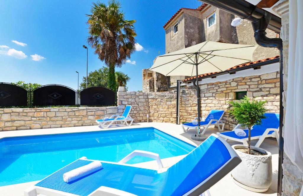 a swimming pool with two chairs and an umbrella at Lory in Sveti Lovreč Pazenatički
