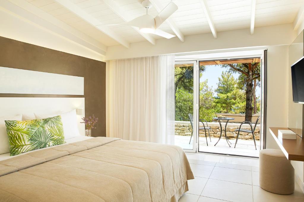 a bedroom with a bed and a balcony with a table at Makryammos in Limenas