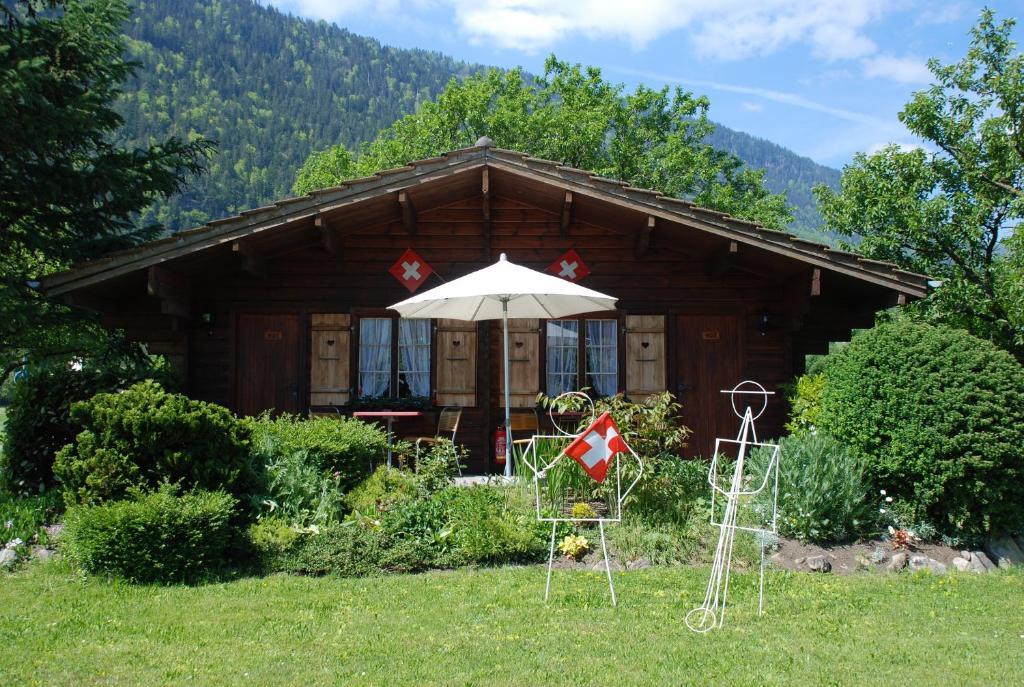 ein Blockhaus mit einem Sonnenschirm und Stühlen davor in der Unterkunft Salzano Basic Rooms Interlaken in Interlaken