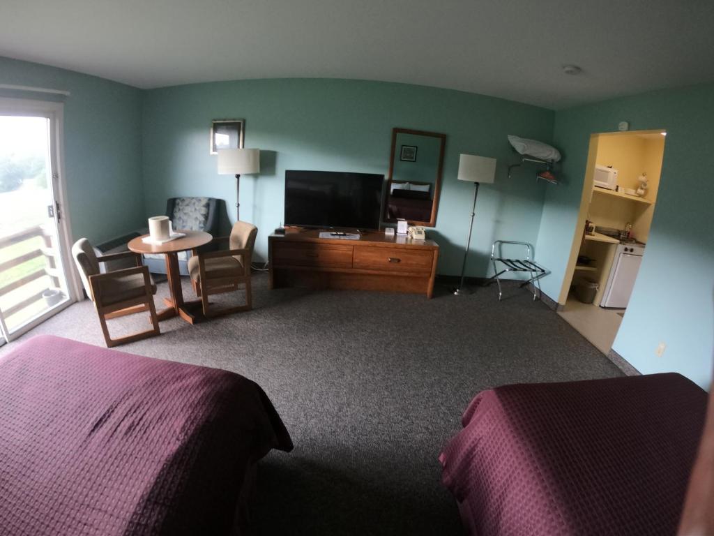 a hotel room with a bedroom with a tv and a desk at Copper Lantern Motor Lodge in West Brookfield