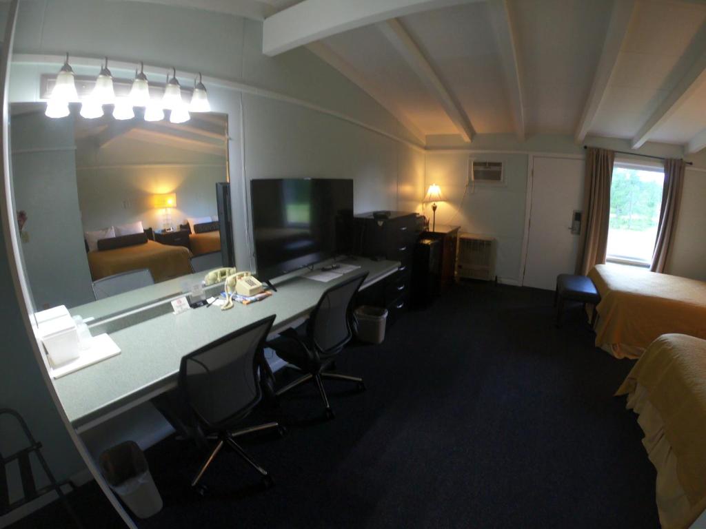 a hotel room with a desk with chairs and a mirror at Copper Lantern Motor Lodge in West Brookfield