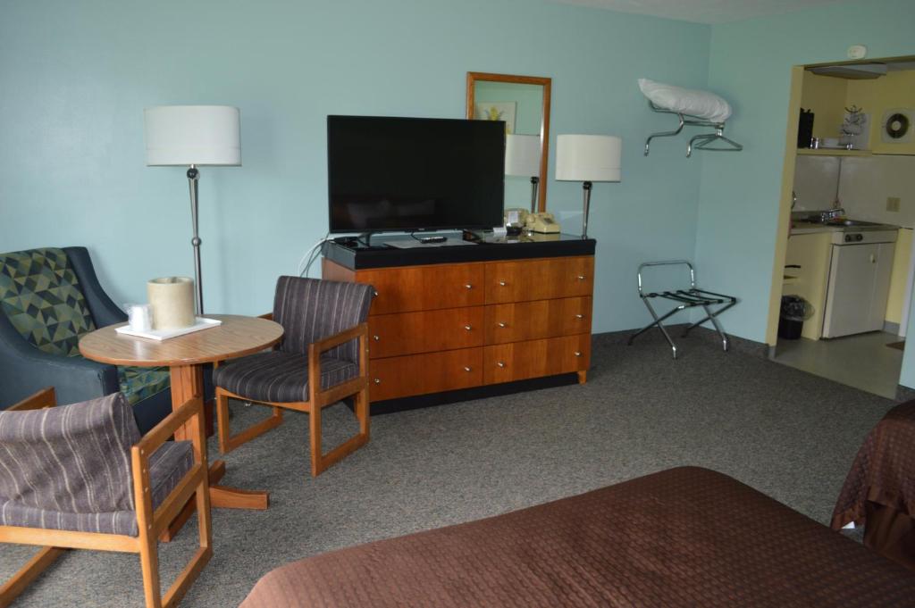 a living room with a tv and a wooden dresser at Copper Lantern Motor Lodge in West Brookfield