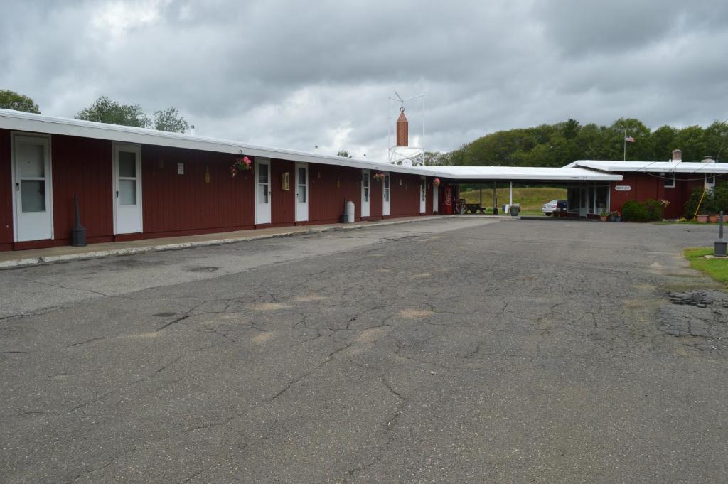 an empty parking lot next to a red building at Copper Lantern Motor Lodge in West Brookfield