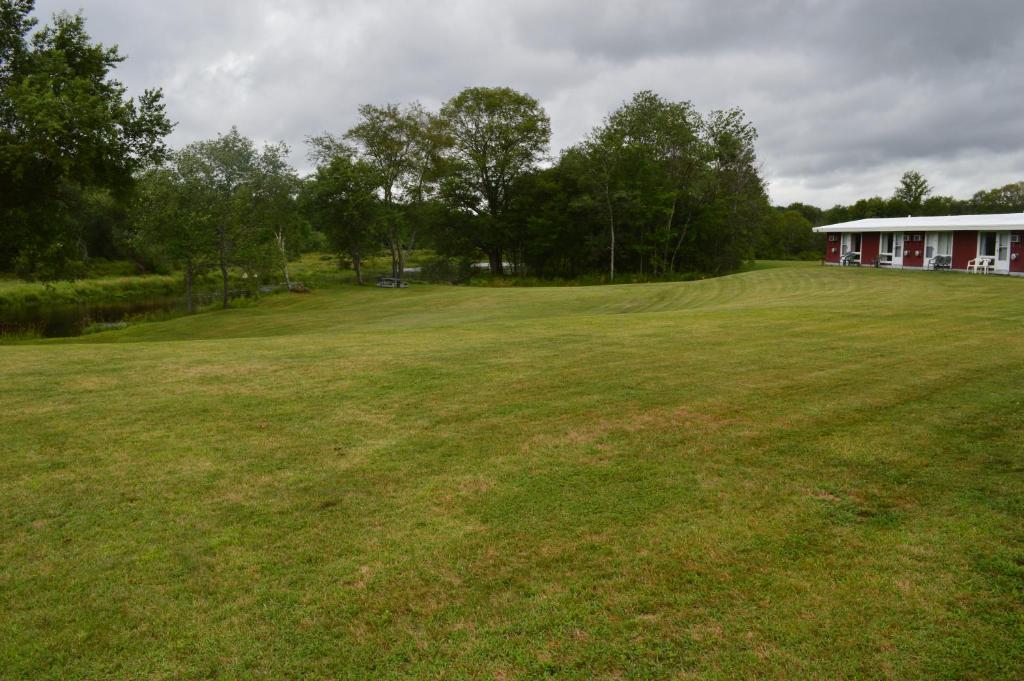 a large grass field with a building in the background at Copper Lantern Motor Lodge in West Brookfield