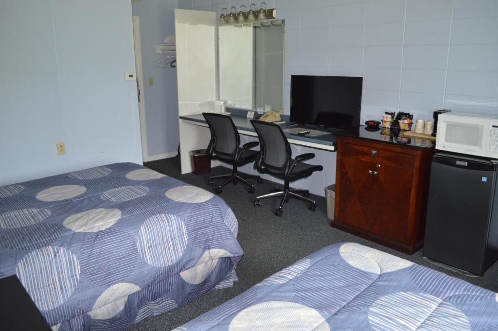 a room with two beds and a desk with a computer at Copper Lantern Motor Lodge in West Brookfield