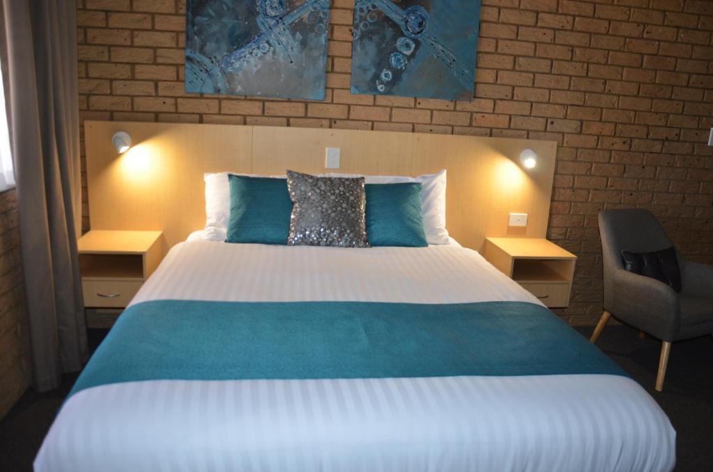 a bedroom with a large bed and a chair at Sunray Motor Inn in Toowoomba
