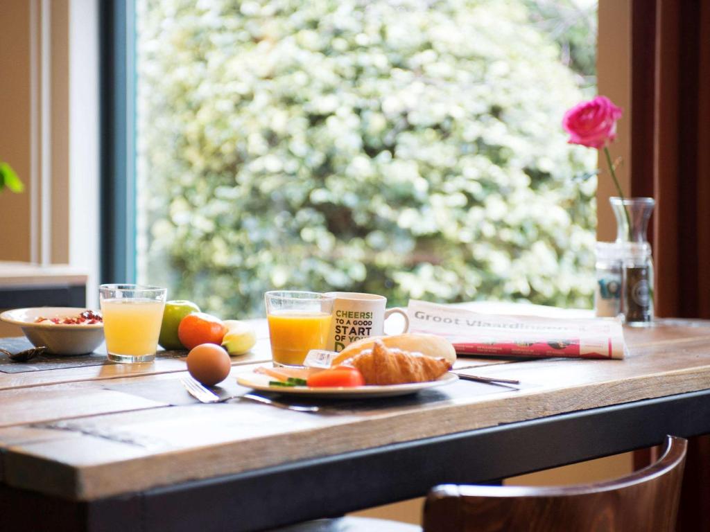 a table with a plate of food and two glasses of orange juice at ibis Rotterdam Vlaardingen in Vlaardingen