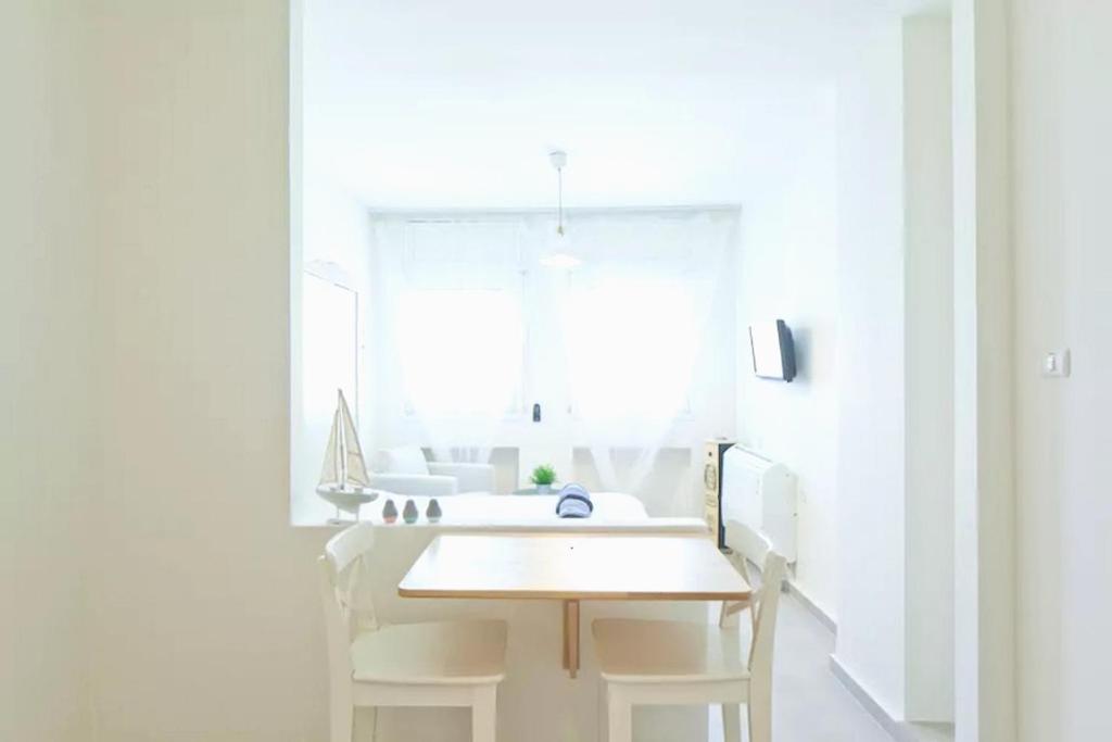 eine weiße Küche mit einem Holztisch und einem Fenster in der Unterkunft Royal Sea Studio in Netanya