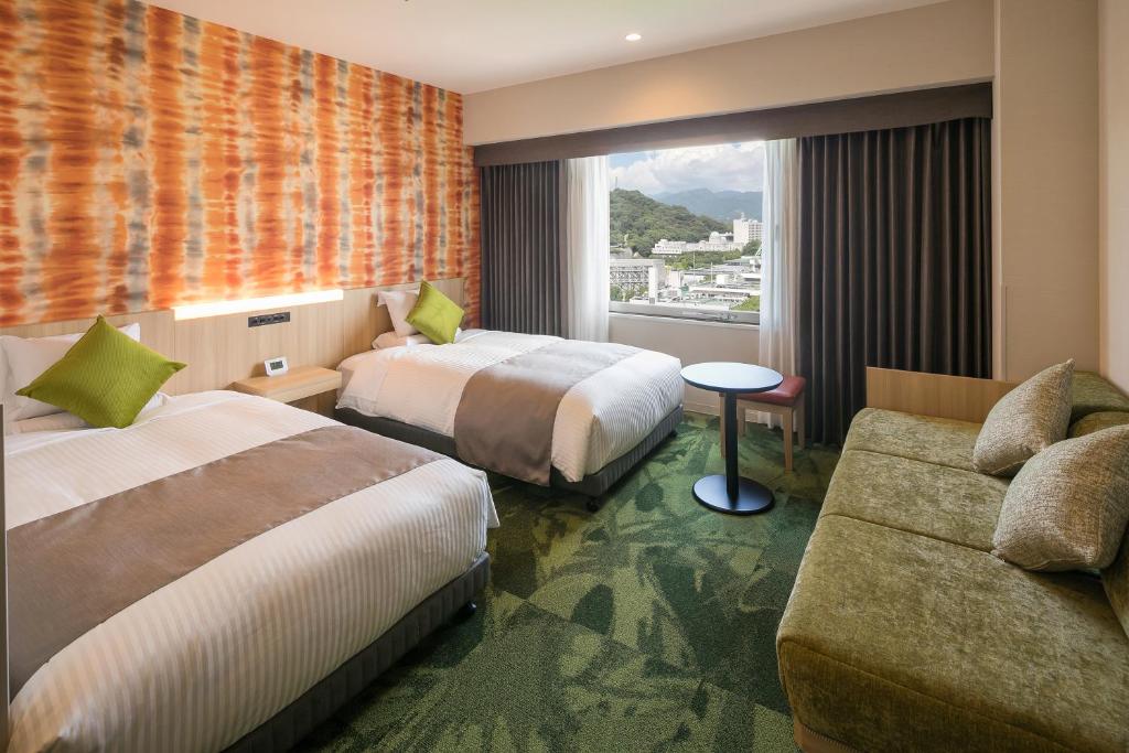 a hotel room with two beds and a couch at HOTEL MYSTAYS Matsuyama in Matsuyama