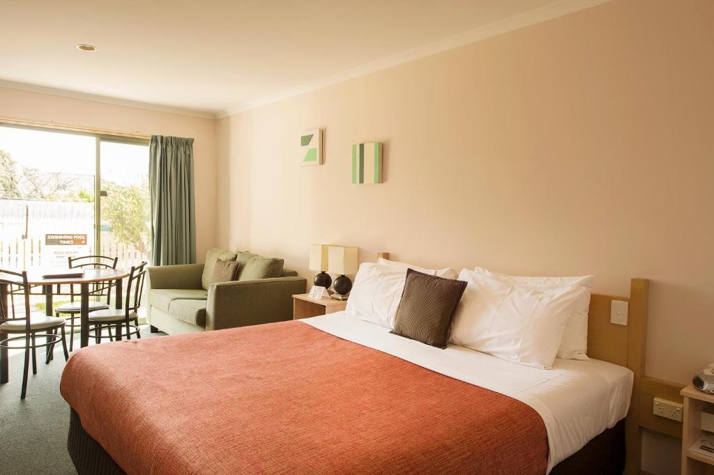 um quarto de hotel com uma cama e uma sala de estar em Rose Garden Motel em Geelong