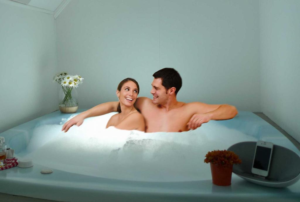 a man and a woman sitting in a bath tub at Rotorua Coachman Spa Motel in Rotorua