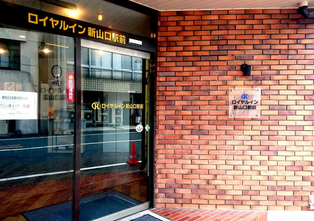 una fachada de ladrillo de una tienda con un cartel en la puerta en Royal Inn Shinyamaguchi Ekimae, en Yamaguchi