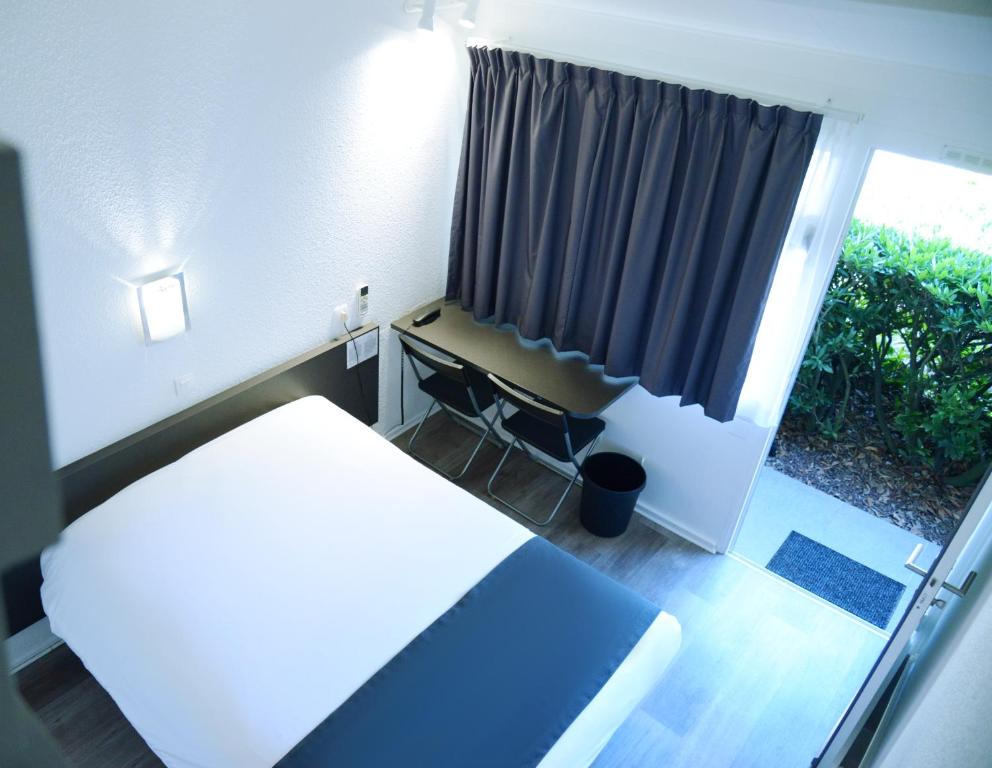 a room with a bed and a window with a desk at Aerel Hotel Aéroport Blagnac in Blagnac