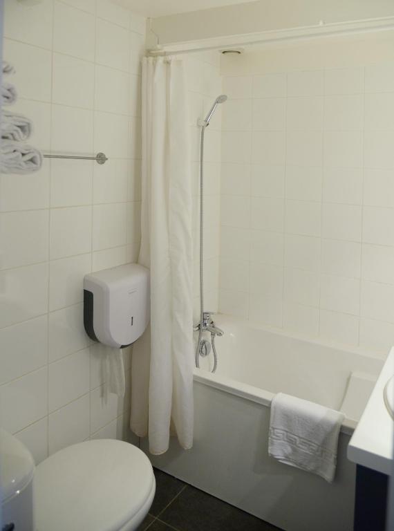 a bathroom with a toilet and a bathtub with a shower curtain at Aerel Hotel Aéroport Blagnac in Blagnac