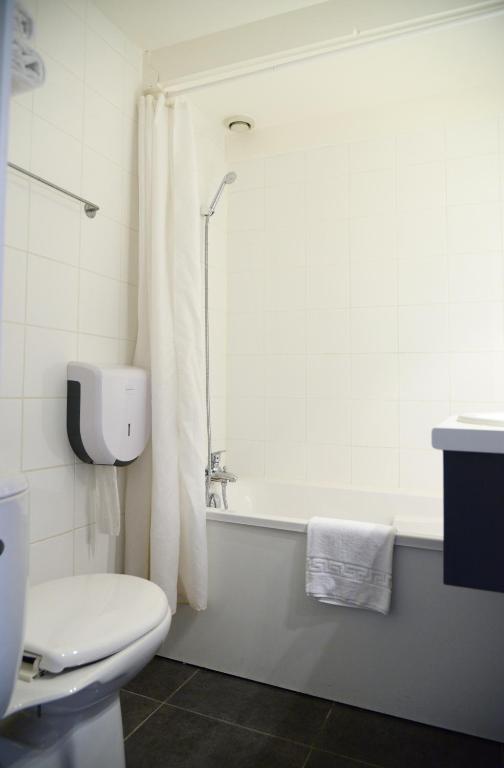 a white bathroom with a toilet and a bath tub at Aerel Hotel Aéroport Blagnac in Blagnac