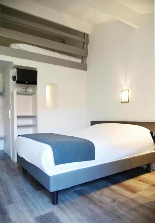 a bedroom with a large white bed and a flat screen tv at Aerel Hotel Aéroport Blagnac in Blagnac