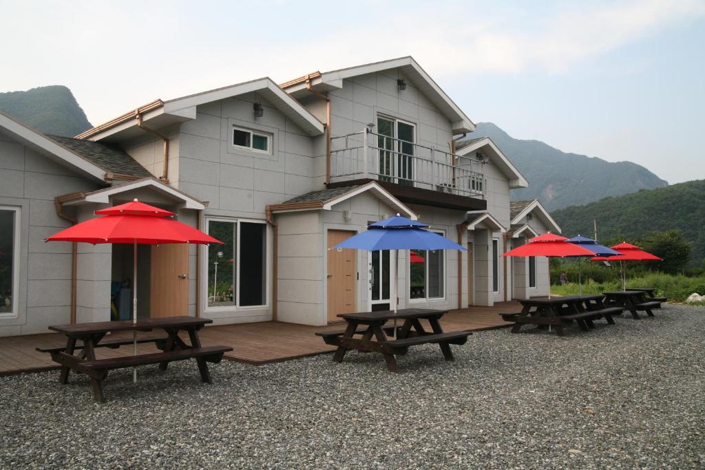 a group of picnic tables with umbrellas in front of a building at Byelgang Pension in Jeongseon