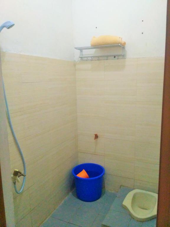 a bathroom with a blue bucket next to a toilet at Homestay Bumi Asri III Cikutra in Bandung