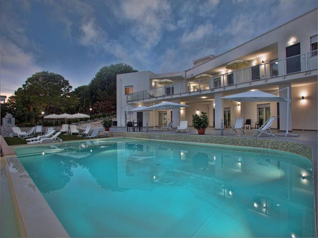 a large swimming pool in front of a house at Cala Del Faro Beach Villas in Cittadella del Capo