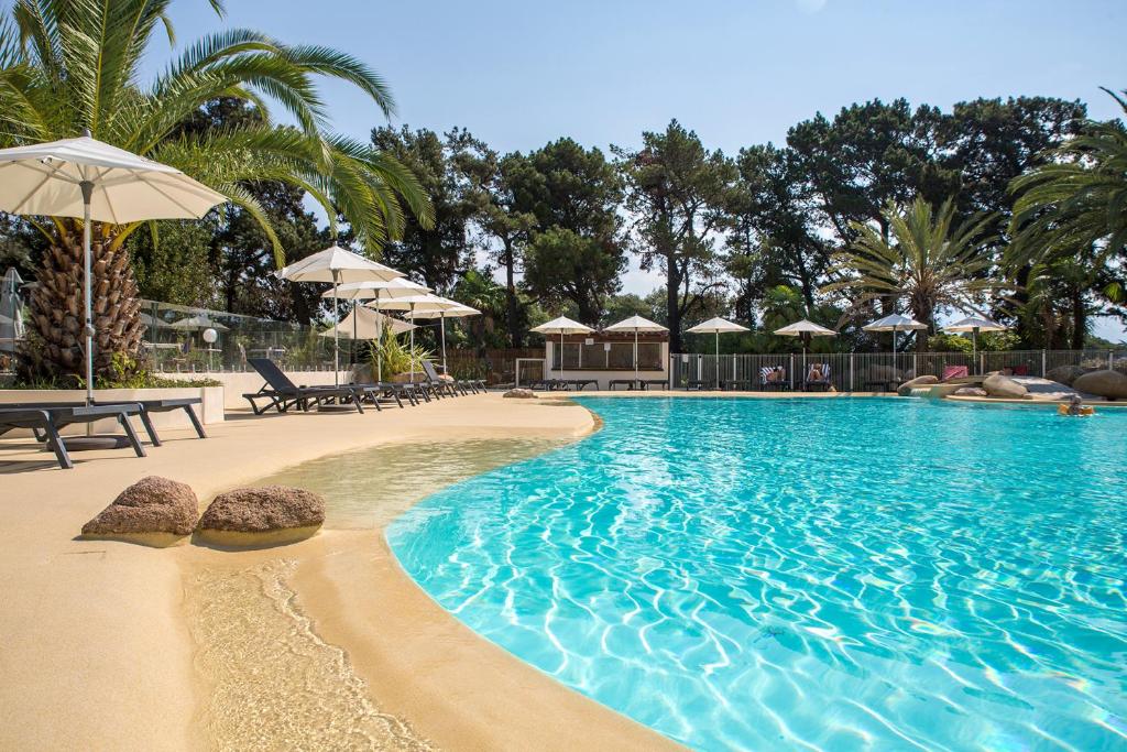 una piscina con spiaggia di sabbia e ombrelloni di Hôtel Campo Dell'oro ad Ajaccio