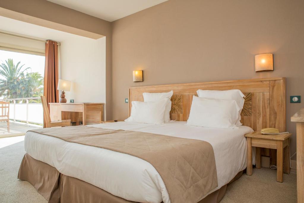 a bedroom with a large bed with white pillows at Hôtel Campo Dell'oro in Ajaccio