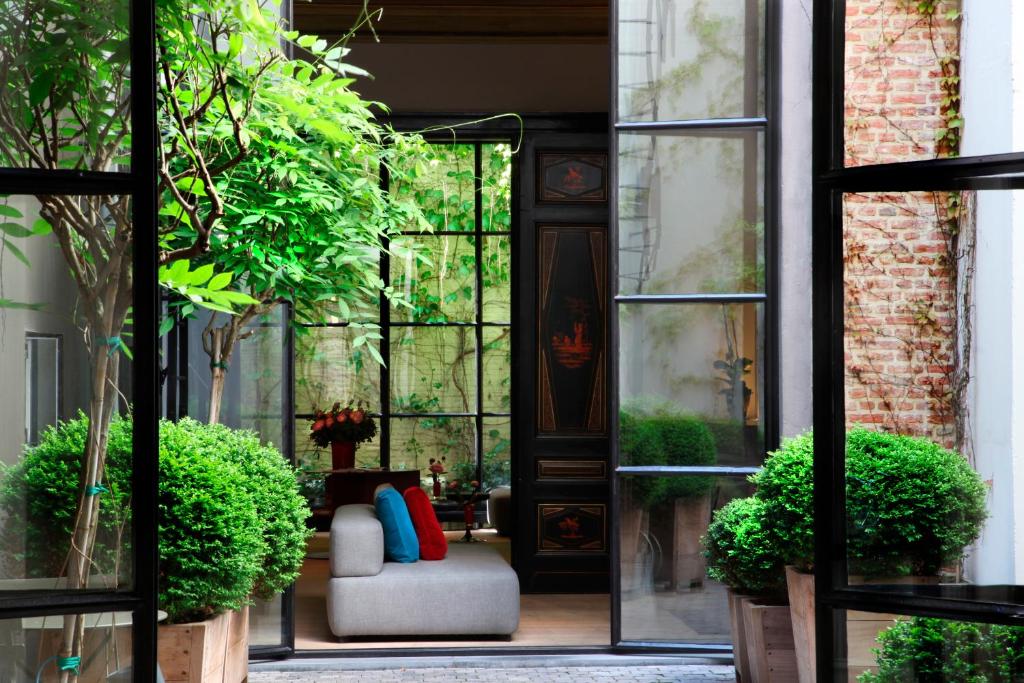 una puerta abierta a un patio con sofá y plantas en Hotel Julien, en Amberes