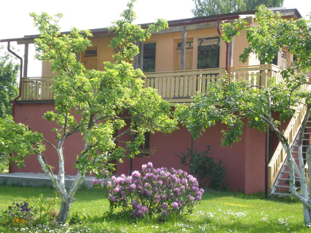 dom z balkonem oraz drzewami i kwiatami w obiekcie Guest House Vītoli w mieście Kolka