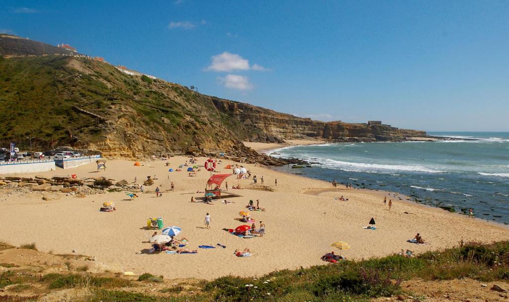 a group of people on a beach near the ocean at Ericeira Surf and Sun in Ericeira