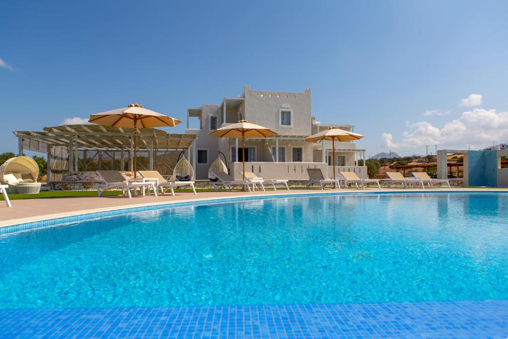 a swimming pool with chairs and umbrellas in front of a building at Sun and Moon Villas in Aliko Beach