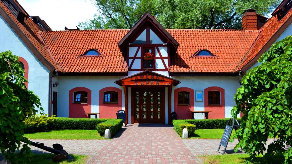 a red and white house with a red roof at Tawerna Kaper in Iława